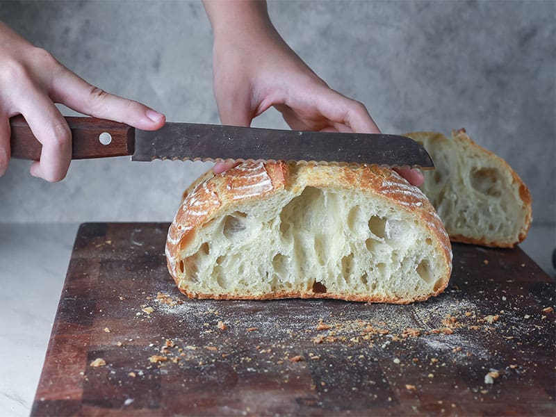 Hands Slicing Sourdough Bread