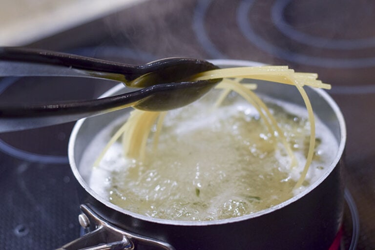 Tongs Holding Spaghetti Boiling