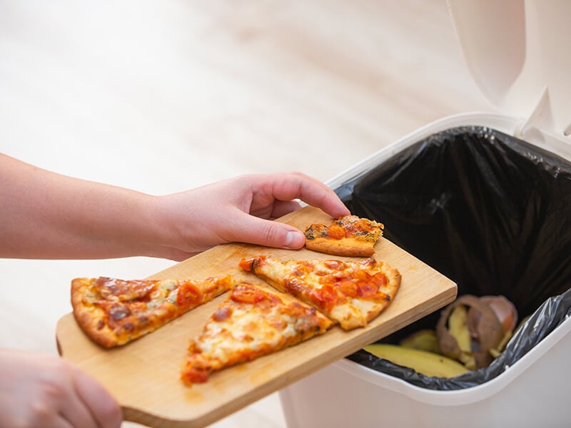 Throwing Old Pizza Into Trash Bin